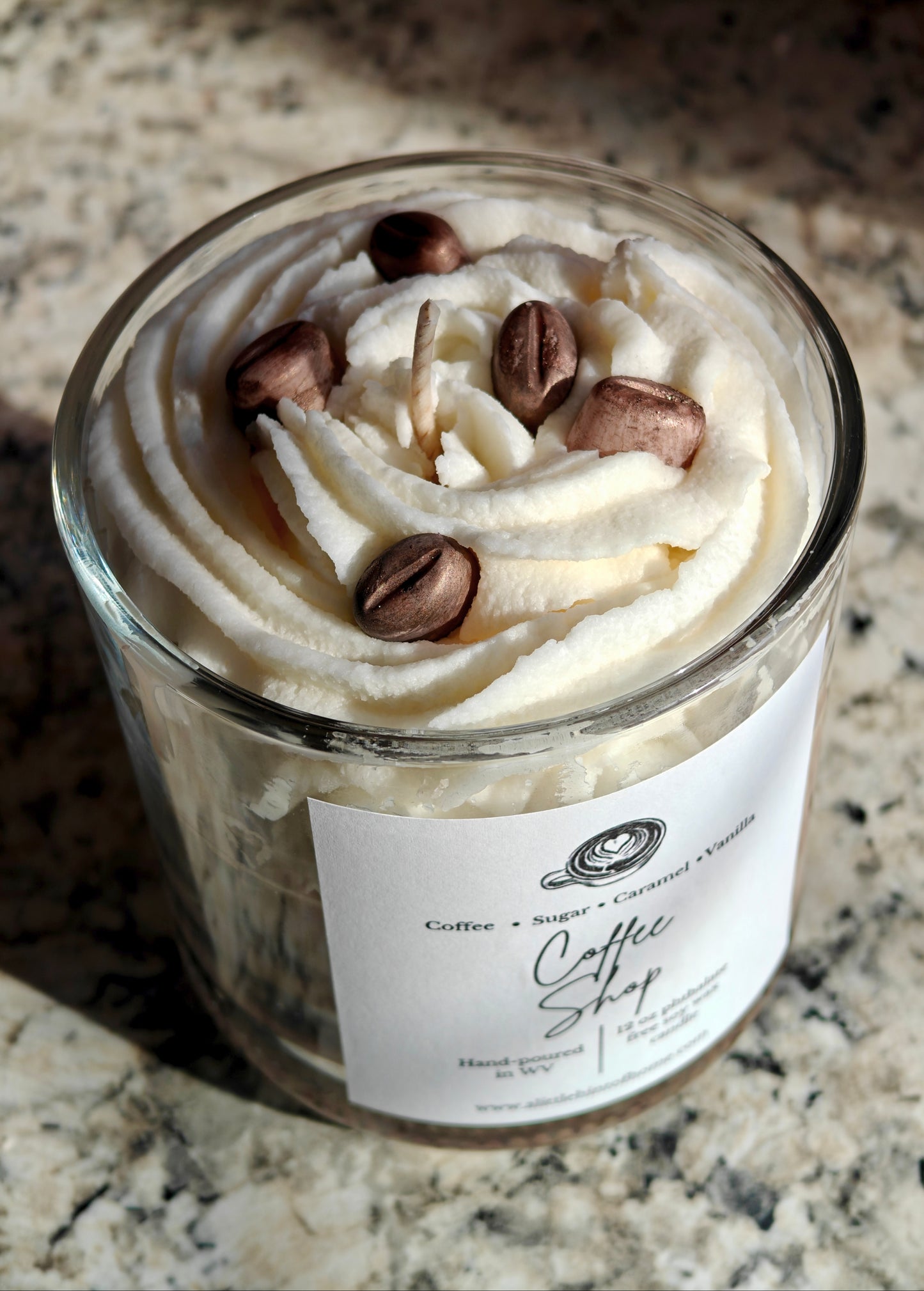 Candle in a glass jar with whipped wax and decorative coffee bean wax embeds on top, labeled 'Coffee Shop', on a marble surface.