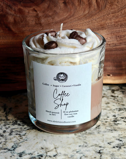 Candle in a glass jar with whipped wax and decorative coffee bean wax embeds on top, labeled 'Coffee Shop', on a marble surface.