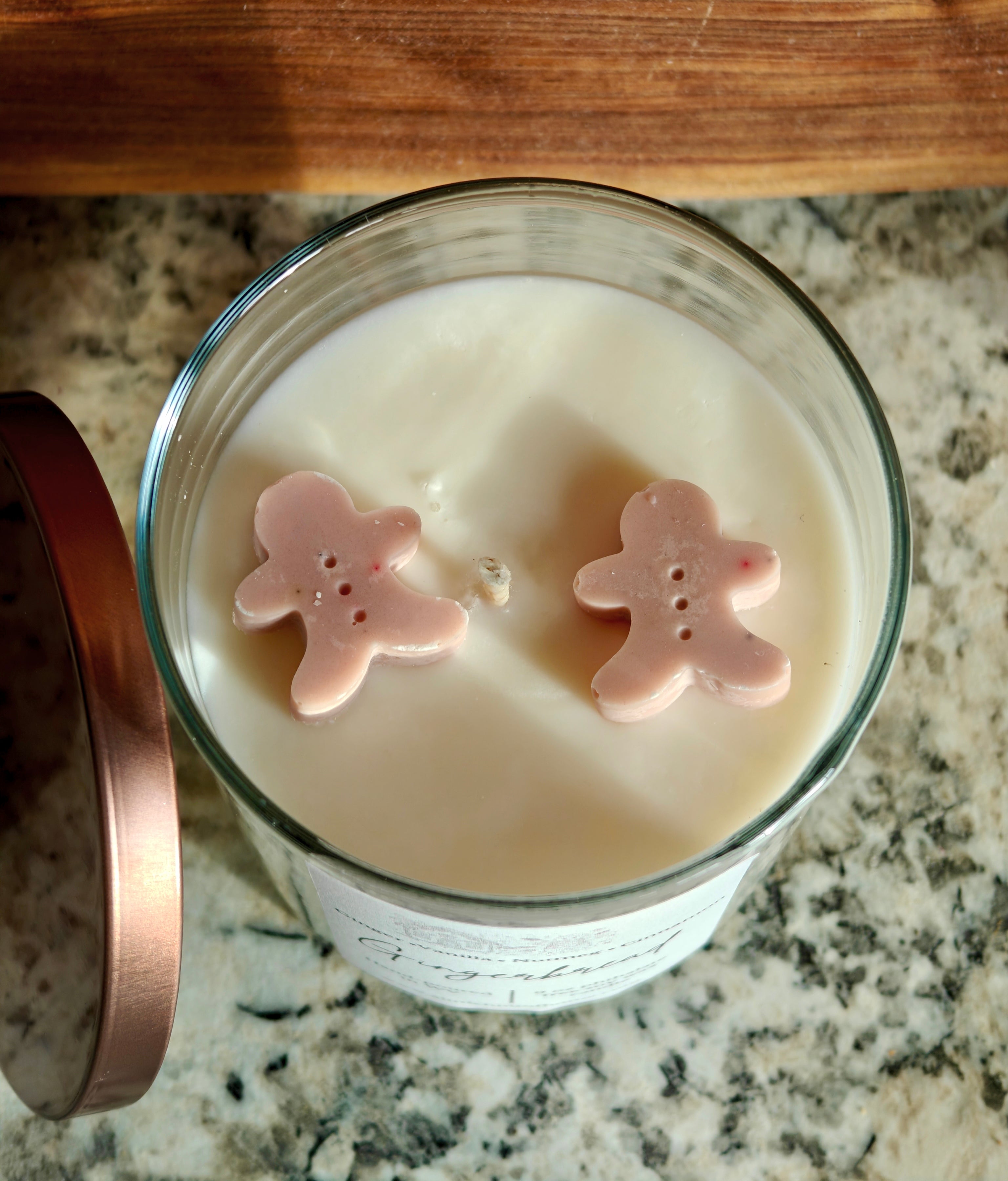 Gingebread soy wax candle with 2 gingerbread wax embeds on top. clear jar with copper lid